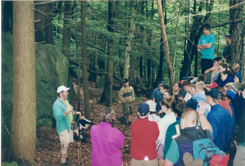 Survival participants listening to a speaker among the trees