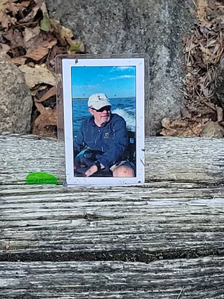 A framed portrait placed on a weathered log at this year’s Survival memorial